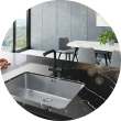 Modern kitchen with a black countertop, sink, and view of dining area and large windows.