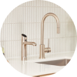 Modern kitchen sink with two sleek faucets against a tiled backsplash.