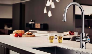 Modern kitchen with a sleek faucet and countertop featuring tomatoes and two glasses of liquid.