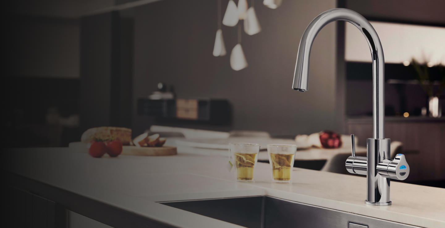 Modern kitchen faucet with drinks and food on a countertop.