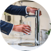 Person filling a glass with water from a modern kitchen tap.