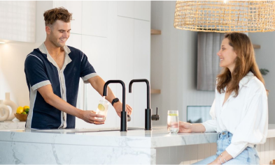 Two people smiling and talking in a bright, modern kitchen.