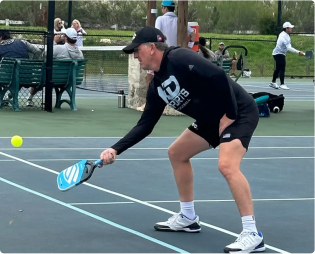 Person playing pickleball on an outdoor court.