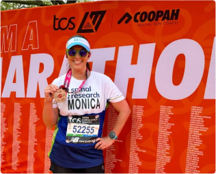 Runner proudly displays finisher medal in front of marathon backdrop.