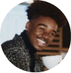 A person smiling while holding a white cup.
