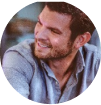 Smiling man with a beard wearing a casual shirt.