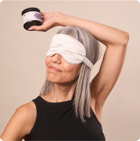 Woman with gray hair wearing sleep mask holding a jar.
