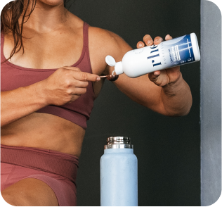 Person in sportswear scooping powdered supplement into a water bottle.