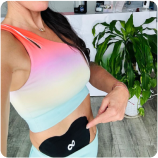 Person in colorful workout attire pointing to a device on their abdomen.