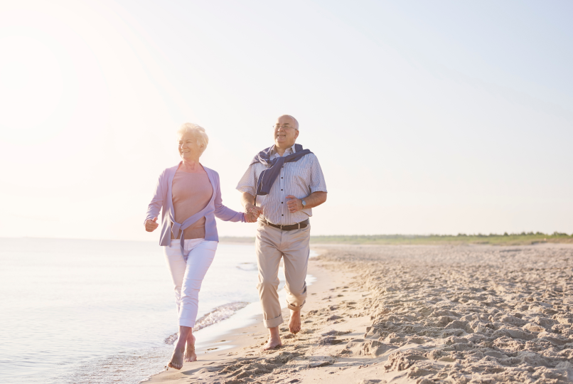 Senior couple walking on a sunny beach.