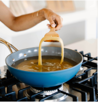 Person cooking pasta in a blue pan on a stove.