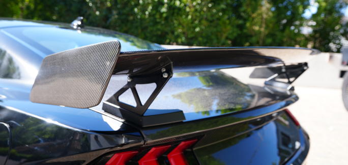 Close-up of a car's rear spoiler with a carbon fiber design.