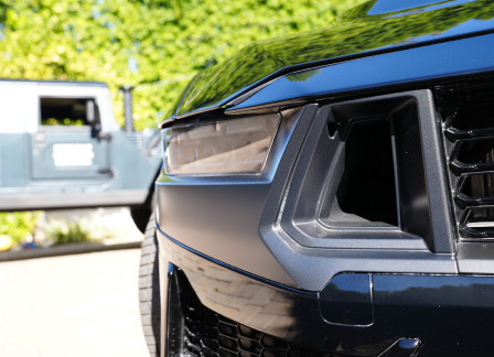 Close-up of a sleek car front, another vehicle in the background.