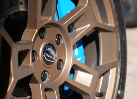 Close-up of a bronze car wheel with a blue brake caliper.