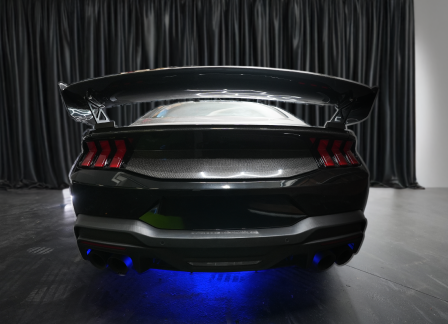 Rear view of a sleek black sports car with illuminated blue underglow.