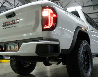 Rear view of a white GMC Canyon pickup truck in a garage.