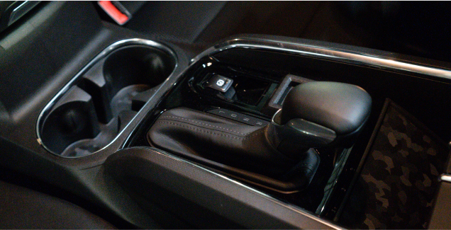 Car interior with gear shifter and cup holders.