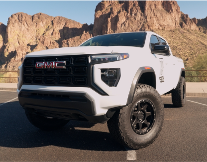 White GMC truck parked in front of rocky landscape.