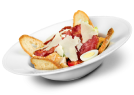 Salad with bacon, parmesan, crostini, and egg slices in a white bowl.