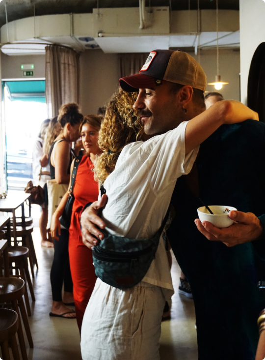People hugging in a cozy café setting with other patrons nearby.