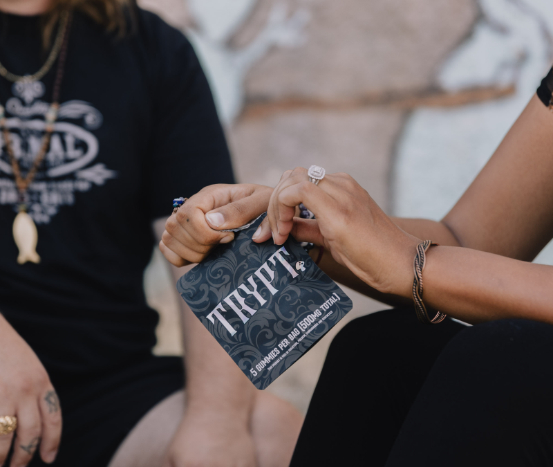 Two people holding a packet labeled 'THYPT' with jewelry and a pendant visible.