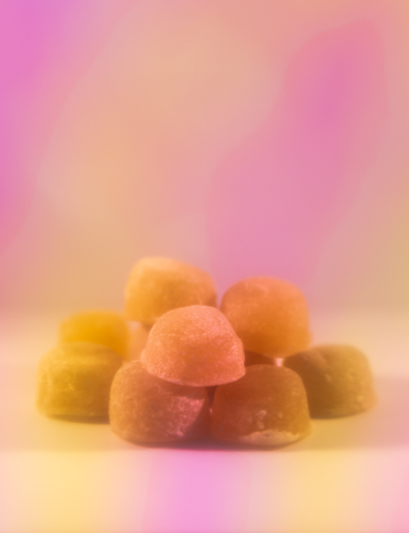 Pile of gumdrop candies with a soft, colorful background.