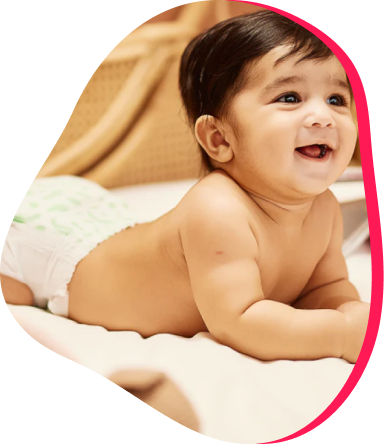 Smiling baby in a diaper lying on a bed.
