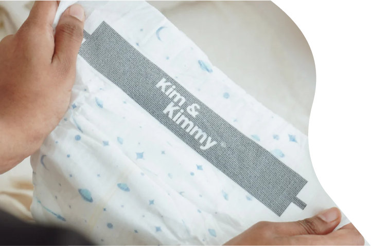 Person holding a white diaper with 'Kim & Kimmy' label.