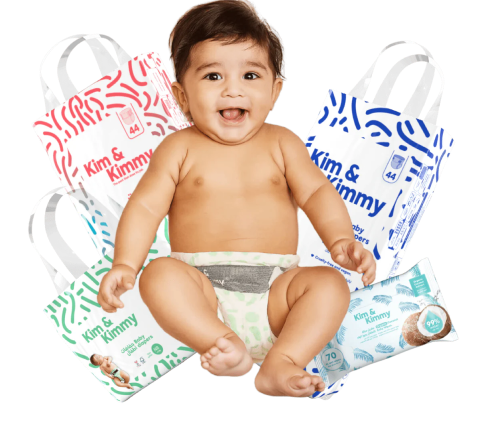 Happy baby sitting among Kim & Kimmy diapers and wipes packages.
