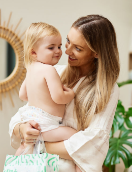 A woman smiling and holding a toddler in her arms.