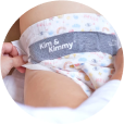 A person adjusting a baby's colorful diaper.