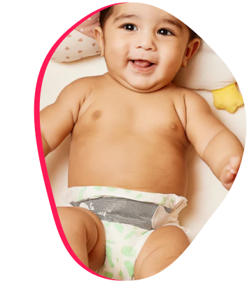 Smiling baby wearing a diaper, lying on a cushion.