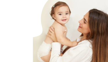 A woman smiling while holding a baby in her arms.