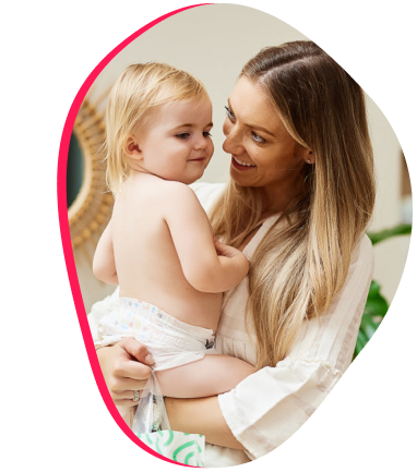 A woman smiling and holding a baby in a diaper.