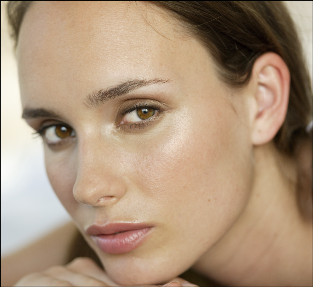 A close-up portrait of a woman with natural makeup and soft lighting.