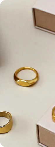Gold rings displayed on a beige surface with pink boxes.