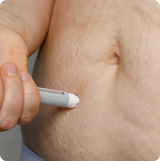 Person administering an injection into their abdomen using an insulin pen.