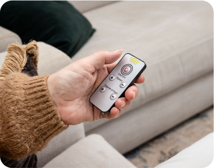 Person holding a small remote control on a beige couch.