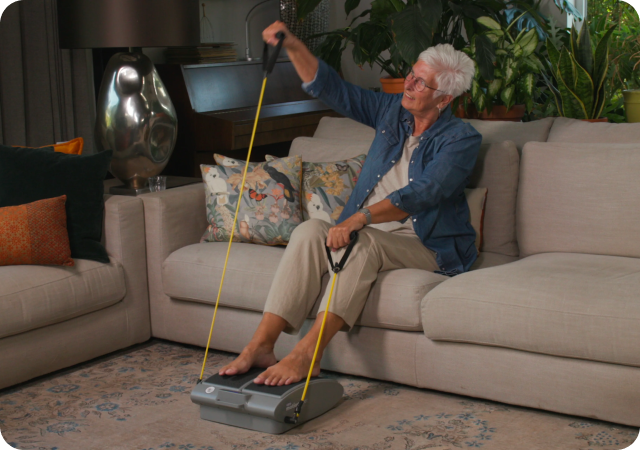 Person exercising with a seated resistance trainer in a living room.