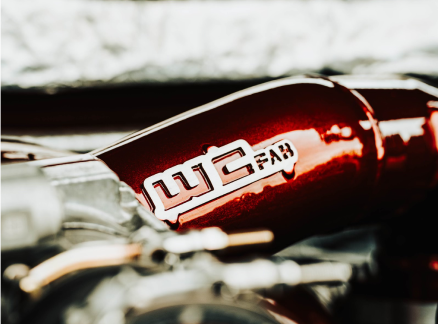 Close-up of a metallic red automotive part with a logo.