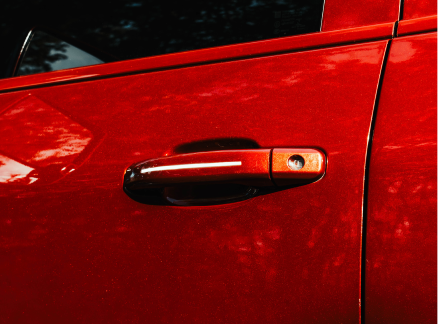 Close-up of a red car door handle with reflection.