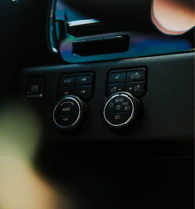 Close-up of car dashboard controls, including air conditioning and headlight settings.