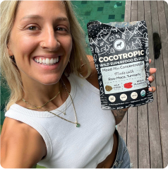 Person holding a packet of Cocotropic Wild Superfood Elixir outdoors.